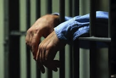 uomo dietro le sbarre della prigione